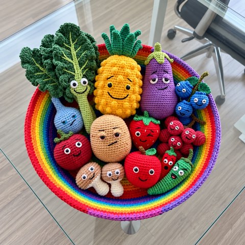 Crochet fruit and vegetable characters arranged in a rainbow