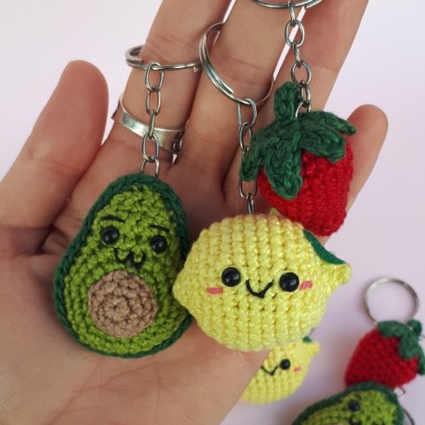 A hand holding crochet avocado and lemon keyrings
