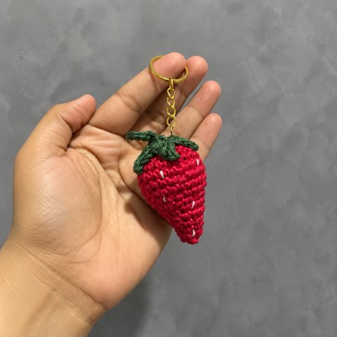 A hand holding a single crochet strawberry keyring