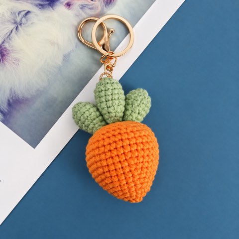 A crochet carrot keyring on a blue and white background