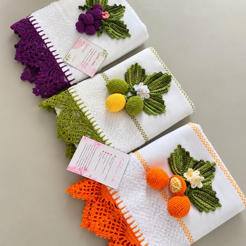 A stack of folded towels trimmed with crochet carrots and strawberries